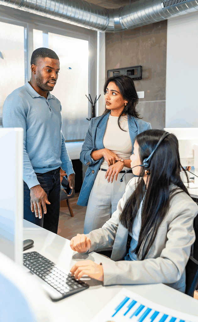 Staff members standing by a desk having a conversation.